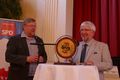 Der Kreisvorsitzende Norbert Maroses überreicht Klaus Stelck ein Sparschwein - mit Inhalt.
